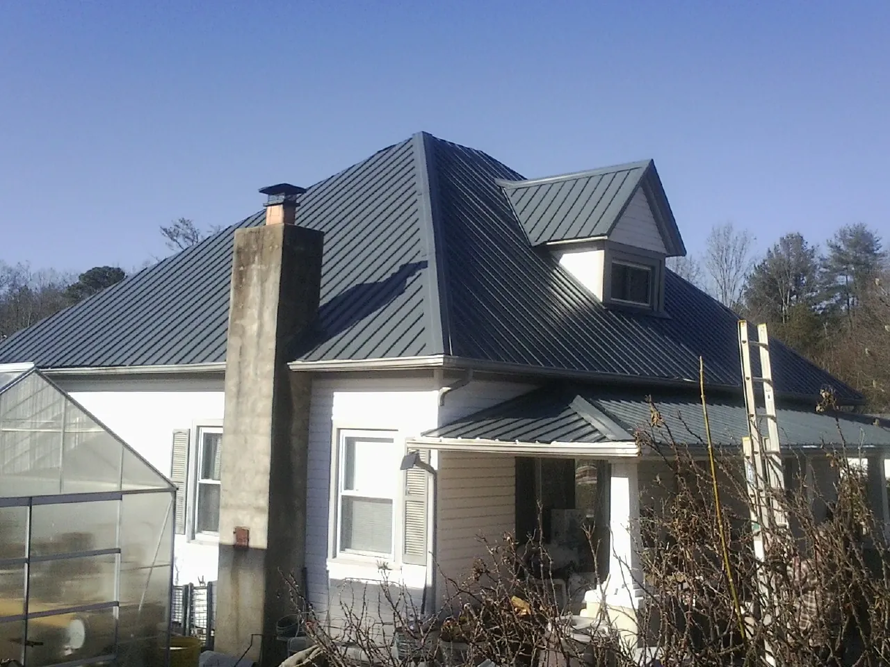 Dark blue standing seam metal roof on a white farmhouse with dormer — Slate & Tile Roof Repair by Roofing Brothers in Campbell Hall
