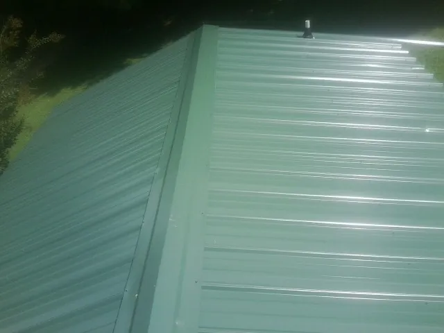 New green metal panels meeting at the ridge of a roof — Flat Roof Repair work by our crew in Campbell Hall