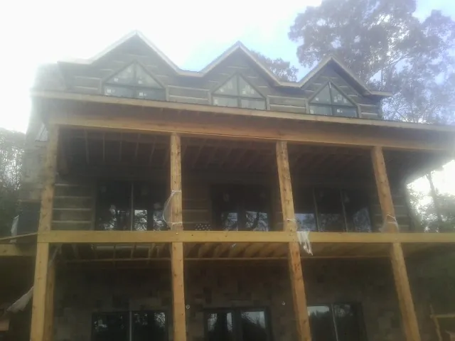Dormers and porch framing on a large log home under construction — Roof Coating work by our crew in Campbell Hall