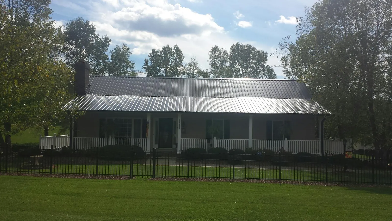 Gray metal roof on a brick ranch with a full width front porch — Gutter Guard Installation work by our crew in Campbell Hall
