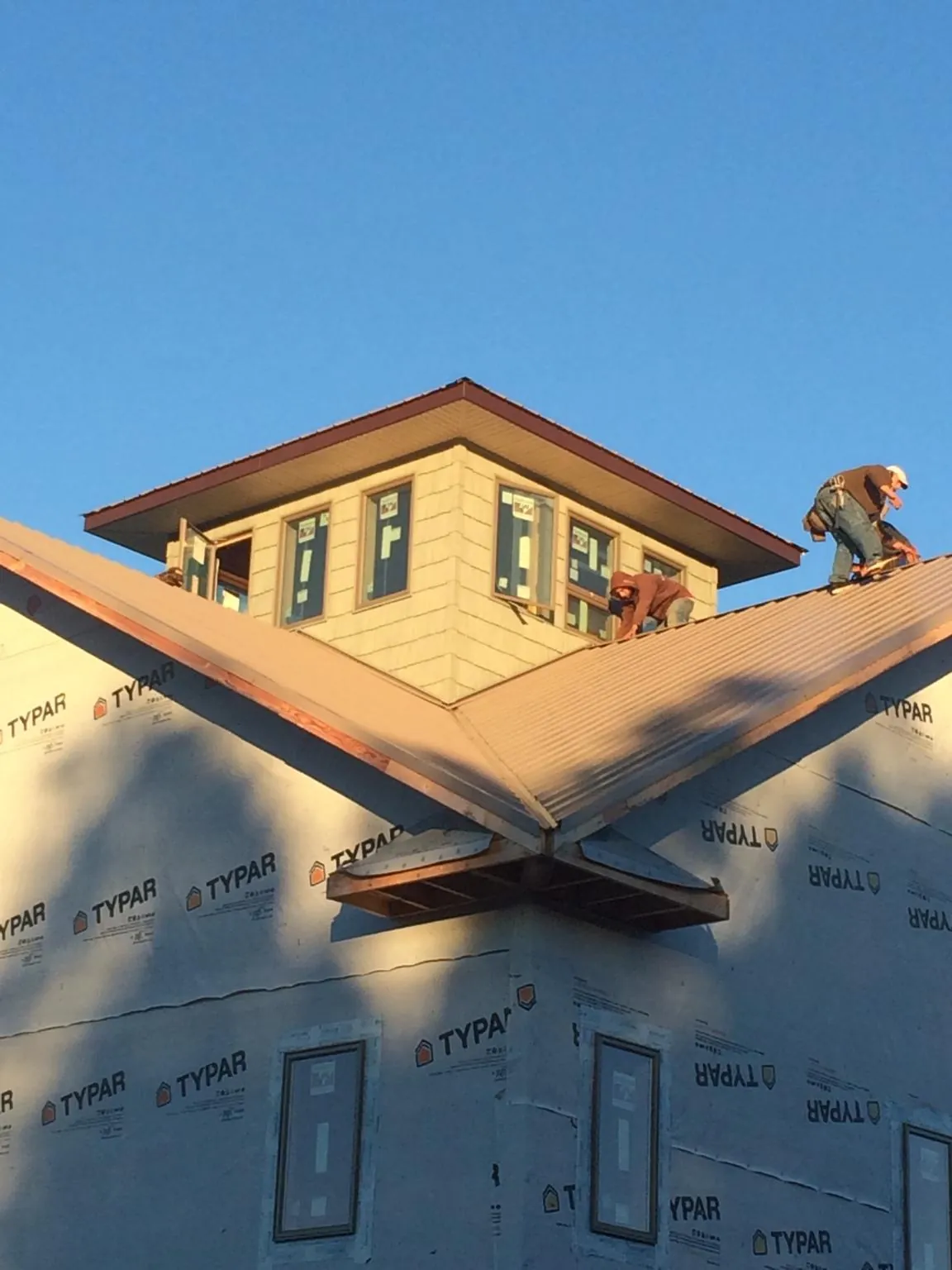 Roofers working around a rooftop cupola on a new metal roof at sunset — Roof Waterproofing in Campbell Hall by Roofing Brothers